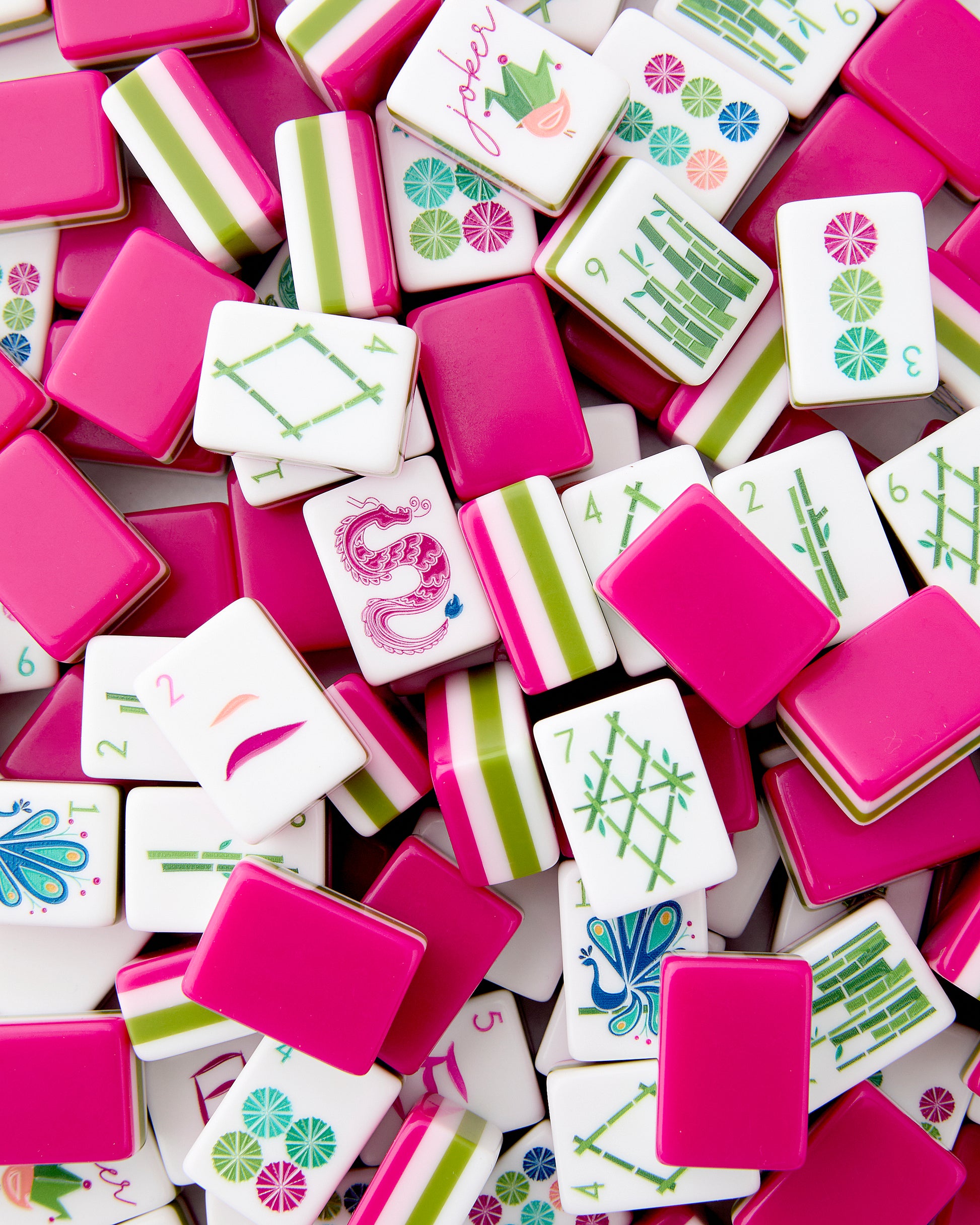 Assorted colorful game tiles with various designs on a pink background